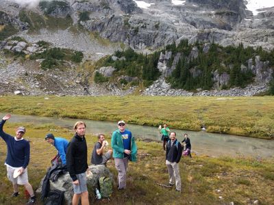 A big group of people who work for Automattic eating lunch in a field near the bottom of Rainbow Mountain in Whistler, British Columbia.