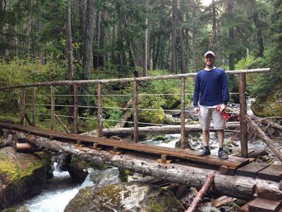 David Kennedy, standing on a bridge in a forest on Skywalk Trail.