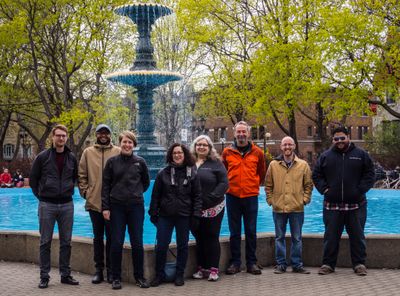 Eight members of the Theme Team standing in front of a fountain.
