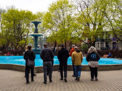 Several members of the Theme Team, backs turned in front of a fountain.